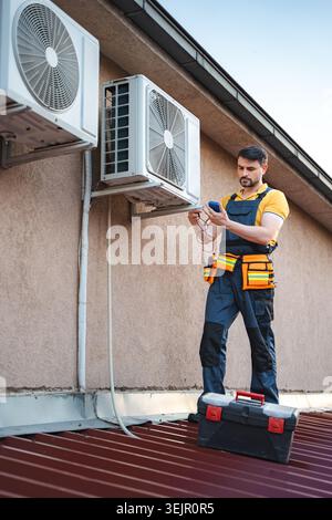 Technician installing and checking air conditioning unit on the roof Stock Photo