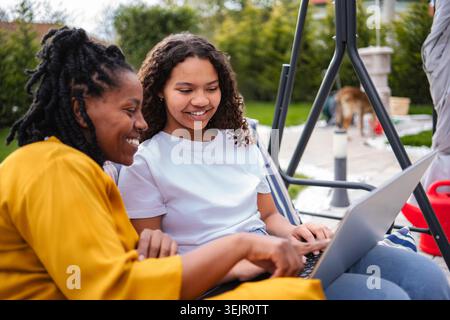 Mother and daughter using laptop together outdoors Stock Photo