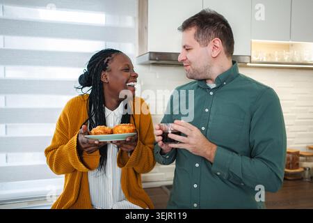 Smiling diverse couple enjoying morning coffee and breakfast Stock Photo