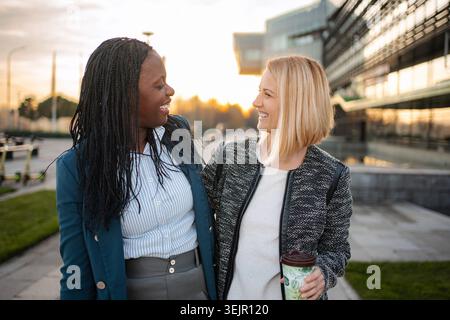 Diverse business women collaborating and smiling outdoors Stock Photo