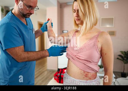 Doctor examining woman with skin rash at home Stock Photo