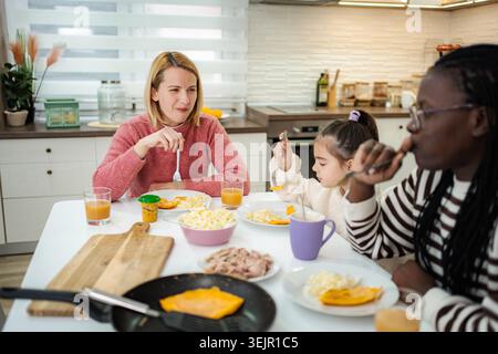 Diverse family enjoying breakfast together at home kitchen table Stock Photo