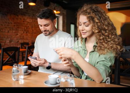 Couple using smartphones in a cafe, ignoring each other Stock Photo