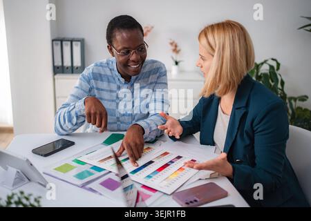 Diverse designers collaborating on color palette for creative project Stock Photo