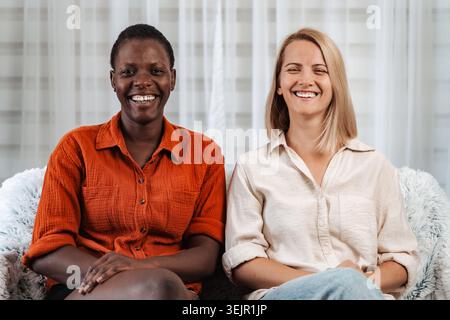 Two happy multi-ethnic women smiling and looking at camera Stock Photo