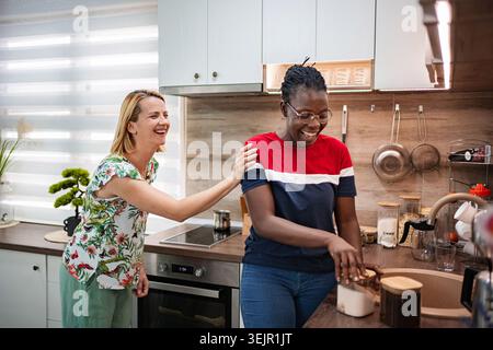 Two friends enjoy a lively moment in a stylish kitchen Stock Photo