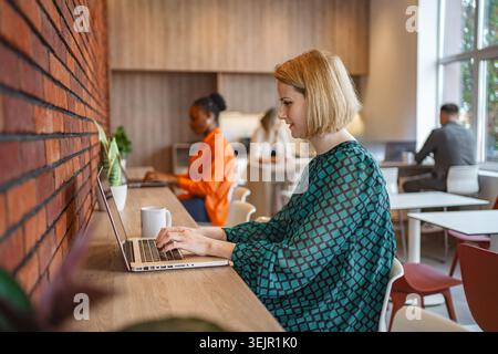 Woman Sitting at Table Using Laptop Computer Stock Photo