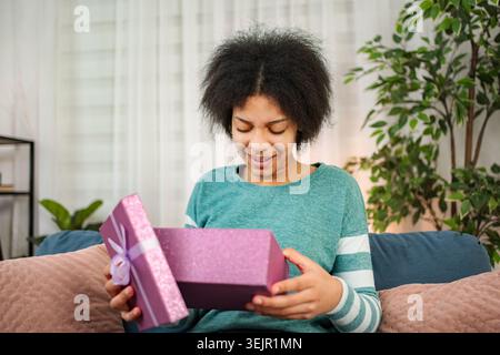 Young woman opening purple gift box with excitement Stock Photo