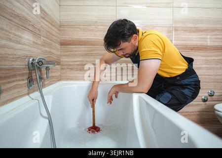 Professional plumber using a force cup to unclog a bathtub drain Stock Photo