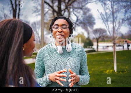 Two young adult women having a conversation in a park setting Stock Photo