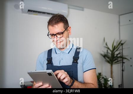 HVAC technician checking air conditioner system with tablet Stock Photo