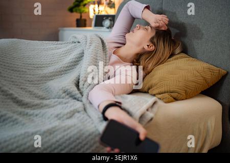 Woman suffering from headache and insomnia problem in bedroom Stock Photo