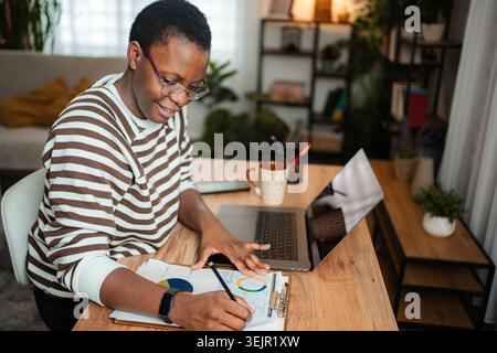 Woman working on laptop and analyzing data at home office Stock Photo