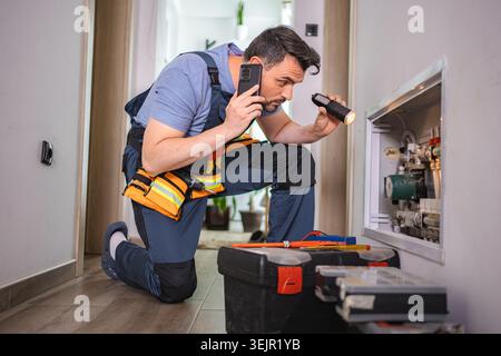 Maintenance worker examining pipes and making a phone call Stock Photo