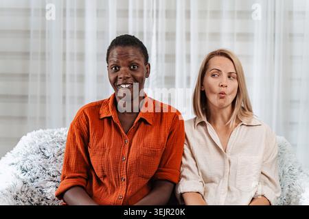 Two female friends making funny faces and smiling at camera Stock Photo