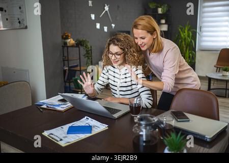 Two female friends talking together on a video call Stock Photo