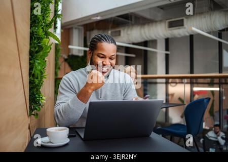 Happy black man celebrating success while working on laptop Stock Photo