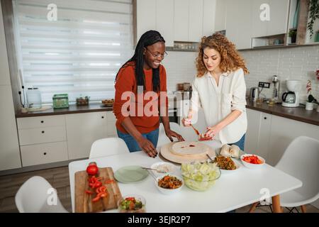 Diverse friends preparing healthy food in modern kitchen Stock Photo