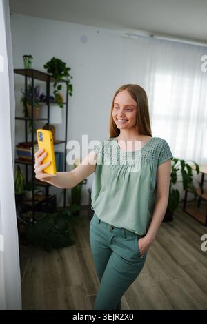 Young woman taking a cheerful selfie in a bright indoor space Stock Photo