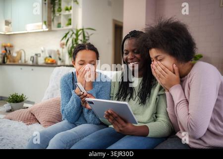 Mother and daughters laughing using tablet for online shopping Stock Photo