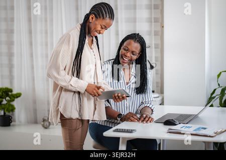 Businesswomen collaborating on tablet in modern office Stock Photo