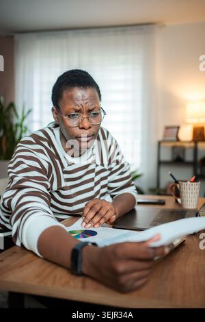 Worried woman working from home checking financial documents Stock Photo