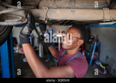 Confident Young Female Mechanic Fixing Car in Auto Repair Shop Stock Photo