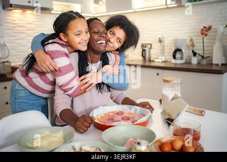 Black mother and daughters enjoying cooking pizza together Stock Photo