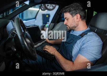 Mechanic using a laptop to diagnose a car's problems Stock Photo