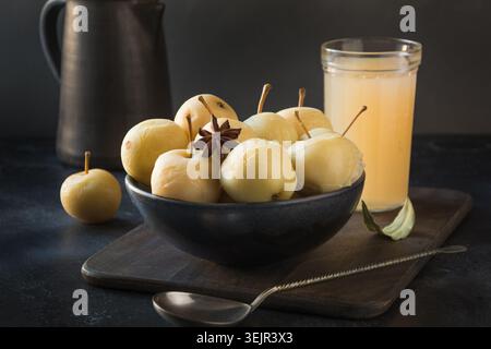 Pickled apples in bowl and apple sidr on dark stone table. Stock Photo