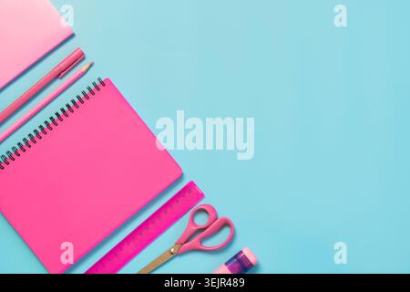 Pink girlish school supplies, notebooks and pens on punchy blue. Stock Photo