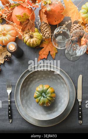 Thanksgiving day table setting with plate decorated fallen leaves, pumpkins. Stock Photo