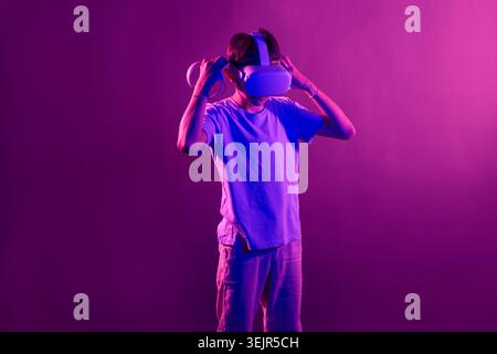 Video Gaming Concept. teenager boy playing with virtual reality goggles, VR headset, modern technology glasses  with neon light Stock Photo