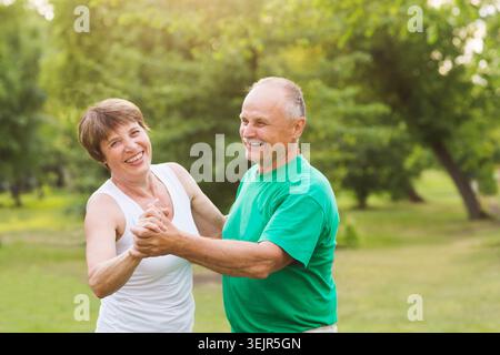 Senior couple dancing in park on sunny day Stock Photo