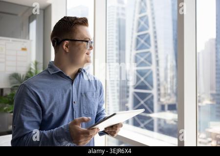 Man with Down syndrome working on tablet in city office Stock Photo