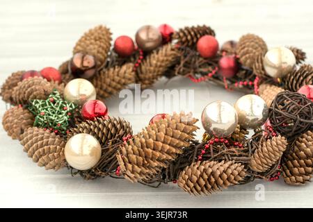 Christmas wreath with red balls and cones on wooden board Stock Photo