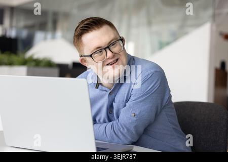 Young 25s professional man with Down syndrome working on laptop Stock Photo