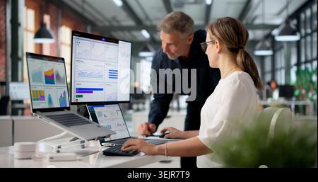 Two Financial Analysts Working Together, Reviewing Data On Dashboard. Stock Photo