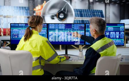 Two Engineers Collaborate On SCADA Screens To Monitor Satellite Assembly. Stock Photo