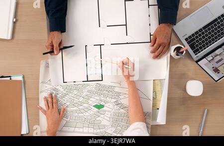 Two Urban Planners Study City Maps On Laptops, Developing New Project Plans. Stock Photo