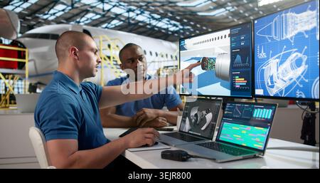 Two Aircraft Technicians In Uniform Use Laptop Repairing Jet Engine Parts. Stock Photo