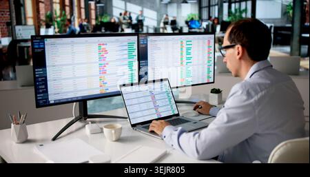 Man At Computer Reviewing Financial Bills And Medical Records In Office. Stock Photo