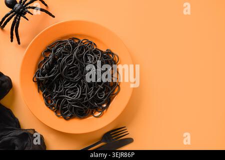 Halloween Italian black pasta decorated funny spiders in orange plate . Stock Photo