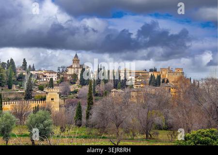 Ancient towers of Alhambra seen from lush Generalife gardens in Granada, Spain. Soft natural light under cloudy overcast sky Stock Photo