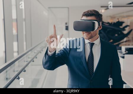 Business man using virtual reality headset in modern office hallway Stock Photo
