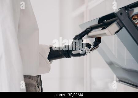 Person with prosthetic hand using touchscreen device at home close up Stock Photo