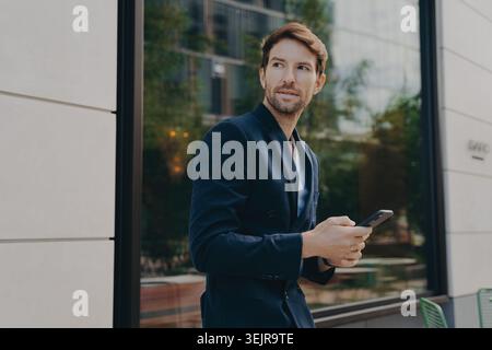 Business man using smartphone outside office building in city Stock Photo