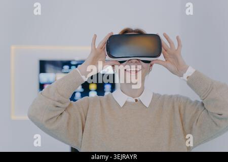 Woman using virtual reality headset at home during immersive VR experience Stock Photo