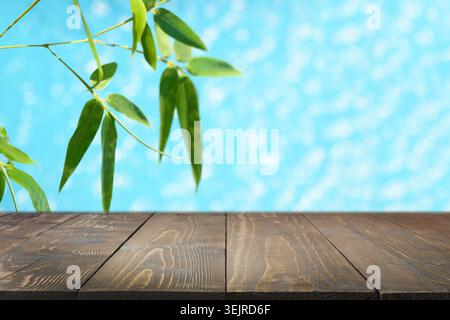 Bamboo Leaves and Empty Wooden Table Top Against Blue Background Stock Photo