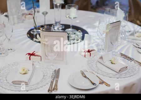 Elegant Wedding Table Setting with White Plates Glassware Menus and Small Gift Boxes at Formal Reception Dinner Celebration Stock Photo